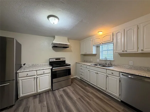 a kitchen with granite countertop a sink stainless steel appliances and cabinets