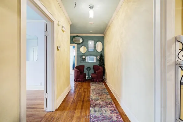 a view of a hallway with wooden floor and a living room