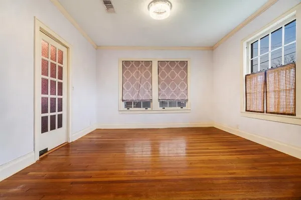 a view of an empty room with wooden floor and a window