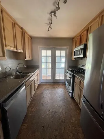 a kitchen with stainless steel appliances a refrigerator a sink a stove top oven and a dishwasher