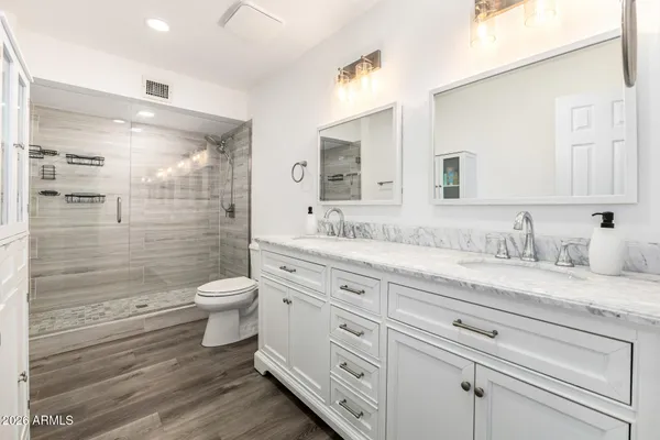 a bathroom with a granite countertop toilet sink shower and a mirror