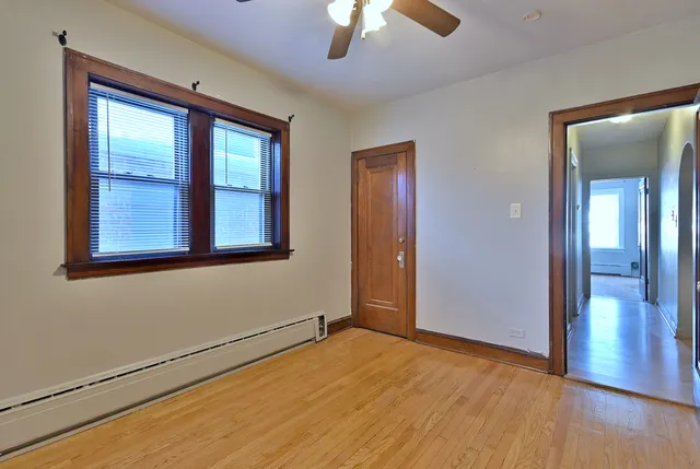 a view of an empty room with a window and wooden floor