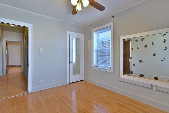 a view of an empty room with a window and wooden floor