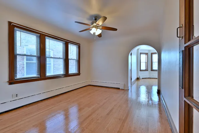 a view of a livingroom with wooden floor a ceiling fan and windows