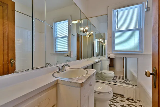 a bathroom with a sink a toilet a mirror and a shower