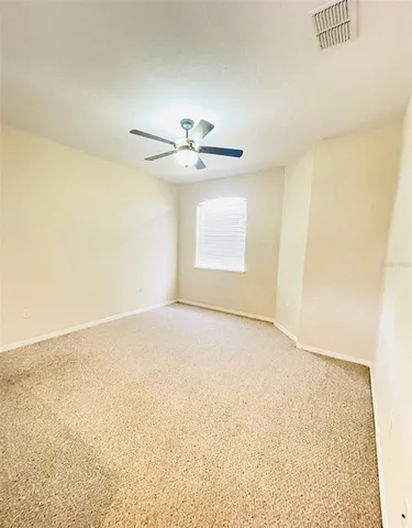 an empty room with a ceiling fan and window
