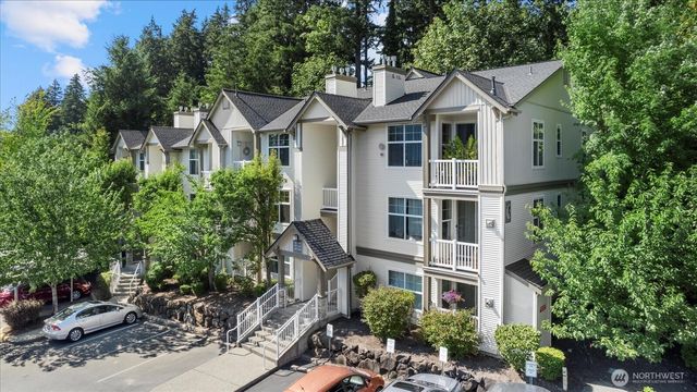 a view of a white house next to a yard with plants and trees