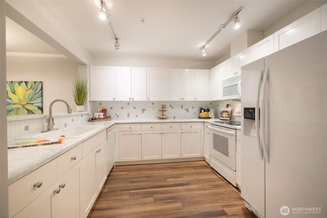 a kitchen with granite countertop white cabinets and white appliances