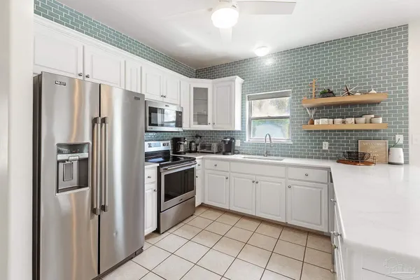 a kitchen with stainless steel appliances a refrigerator a stove a sink and white cabinets