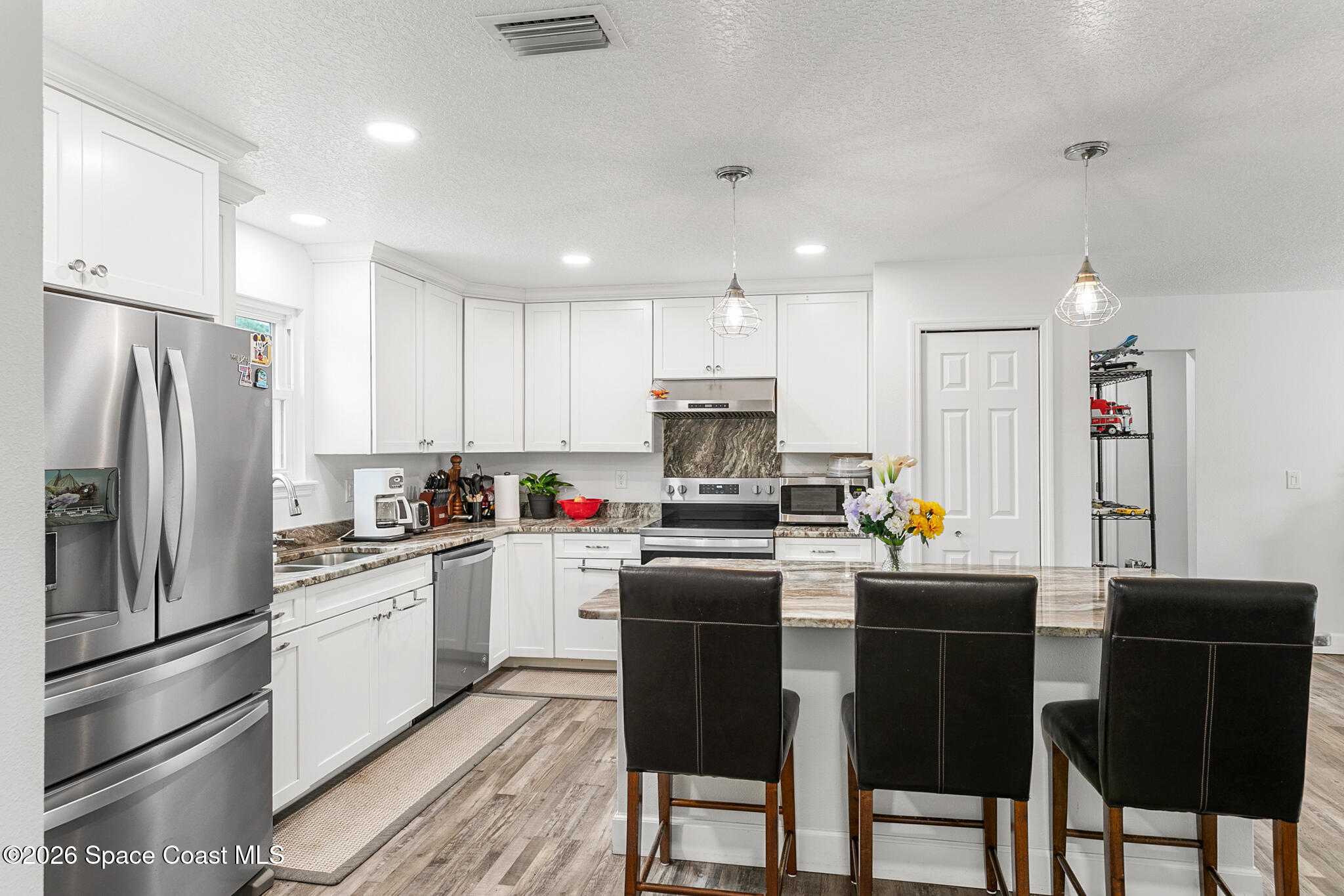 4310 Sand Point Road Grant Valkaria, FL 32949 - Photo 11 of 50 a kitchen with stainless steel appliances a refrigerator stove microwave and cabinets
