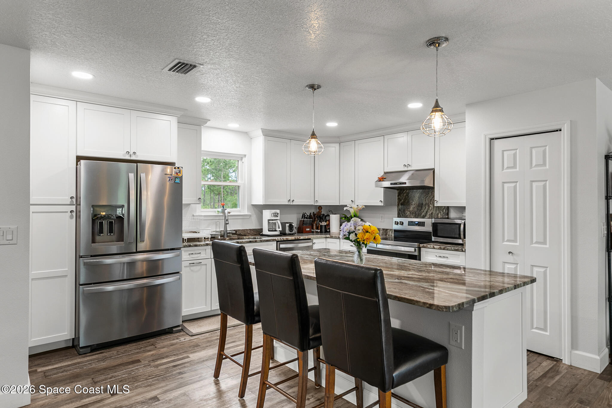 4310 Sand Point Road Grant Valkaria, FL 32949 - Photo 14 of 50 a kitchen with refrigerator and chairs