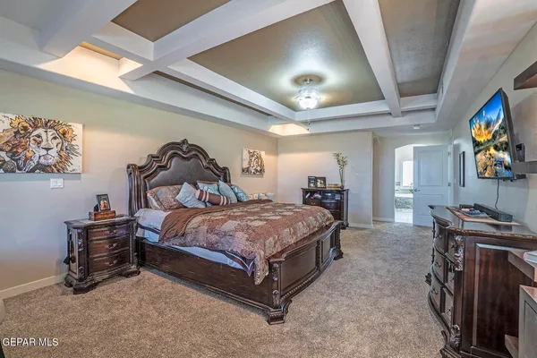 a bedroom with a bed and a flat tv screen on dresser