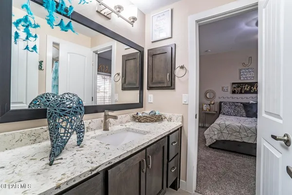 a en suite bathroom with a granite countertop sink and a mirror