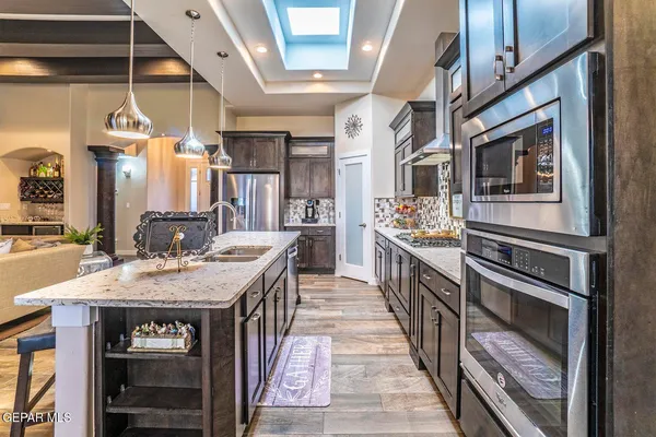 a kitchen with stainless steel appliances granite countertop a kitchen island a stove a sink and a refrigerator