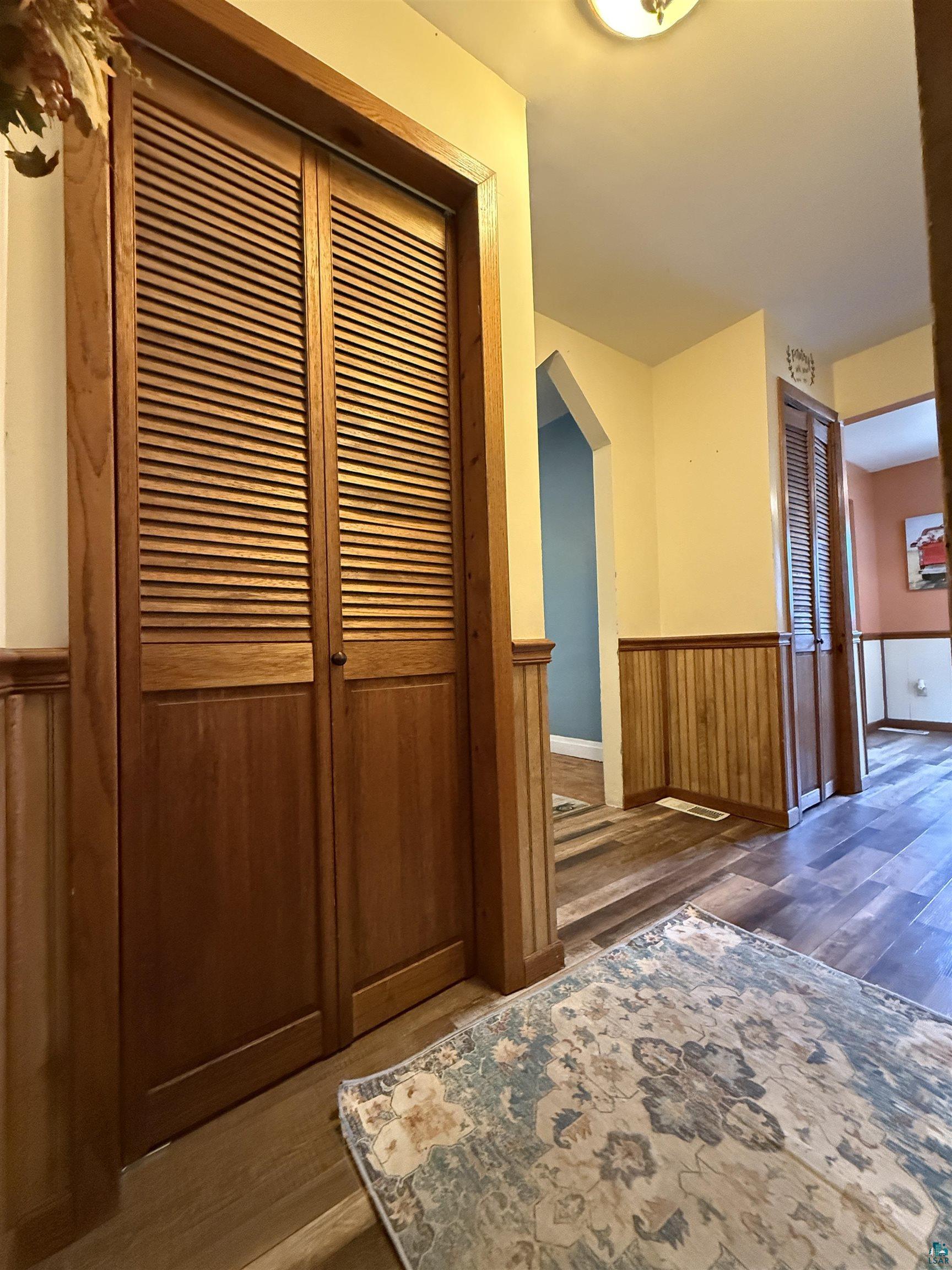 809 16th Street North Virginia, MN 55792 - Photo 25 of 44 Hallway with wood finished floors, a wainscoted wall, arched walkways, and wood walls