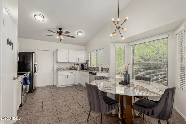a kitchen with stainless steel appliances kitchen island granite countertop a dining table chairs and white cabinets