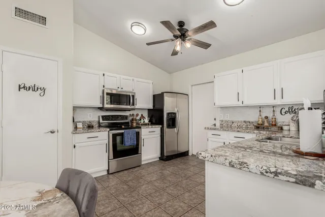 a kitchen with granite countertop a refrigerator stove top oven and sink