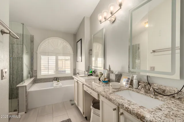 a bathroom with a granite countertop bathtub a double vanity sink a vanity and a large mirror