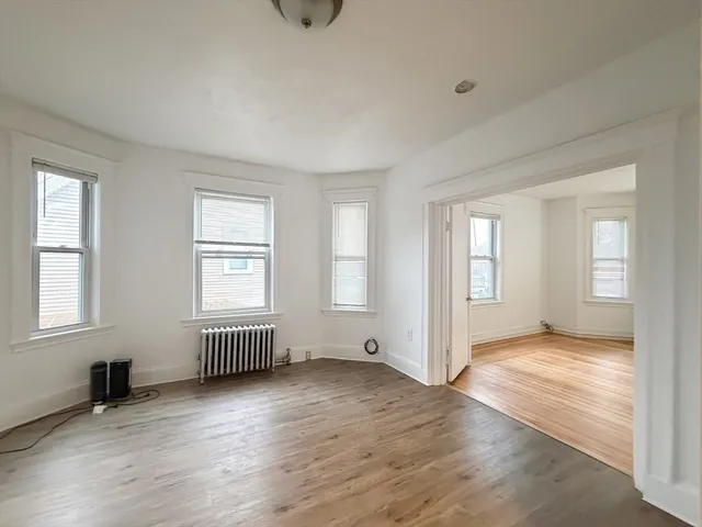 an empty room with wooden floor and windows