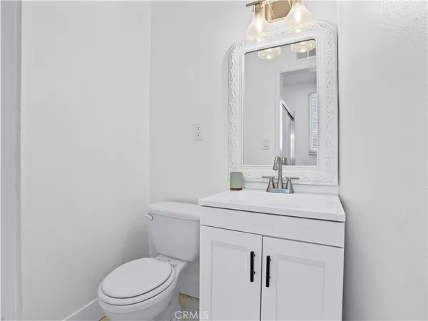 a bathroom with a toilet sink vanity and mirror
