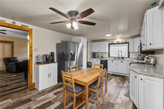 a kitchen with stainless steel appliances kitchen island granite countertop a refrigerator a stove a sink a dining table and chairs with wooden floor