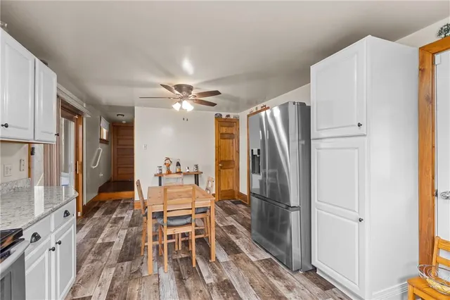 a dining room with stainless steel appliances a refrigerator and a wooden floor