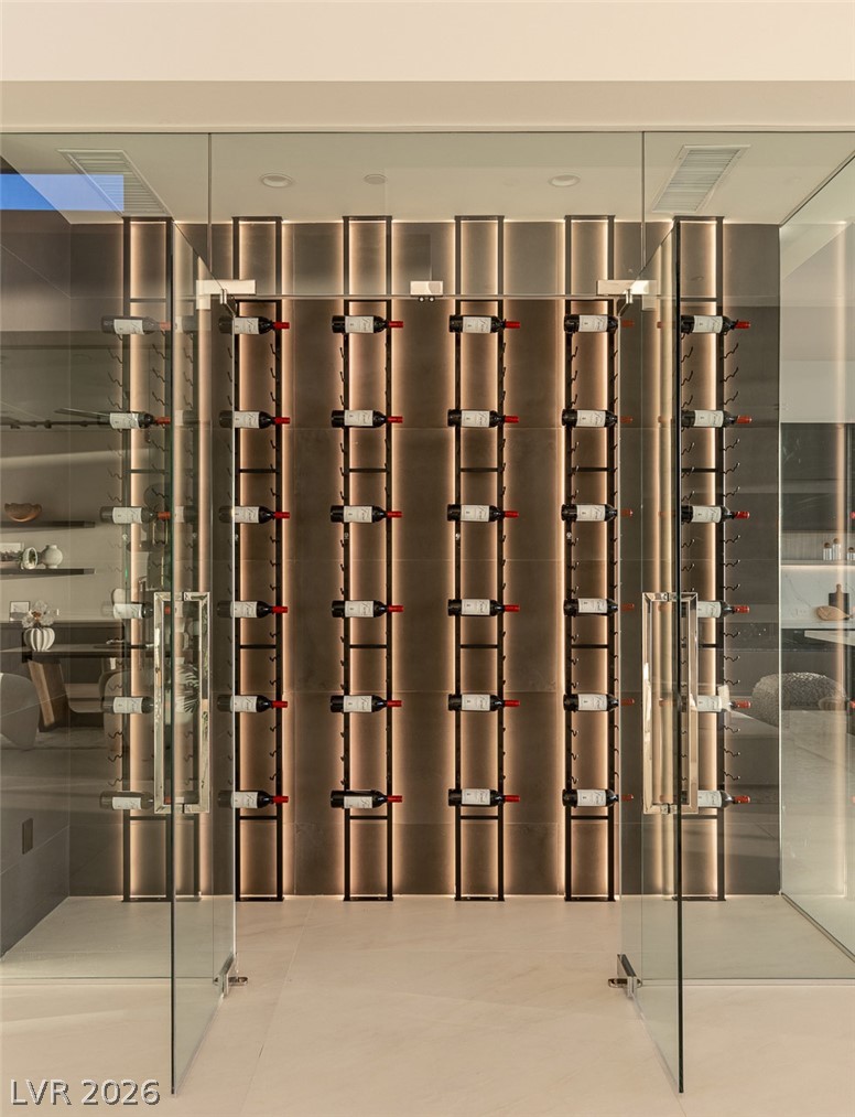 563 Grand Rim Drive Henderson, NV 89012 - Photo 20 of 70 An illuminated wine cellar, encased in glass, provides an elegant display for a curated collection.