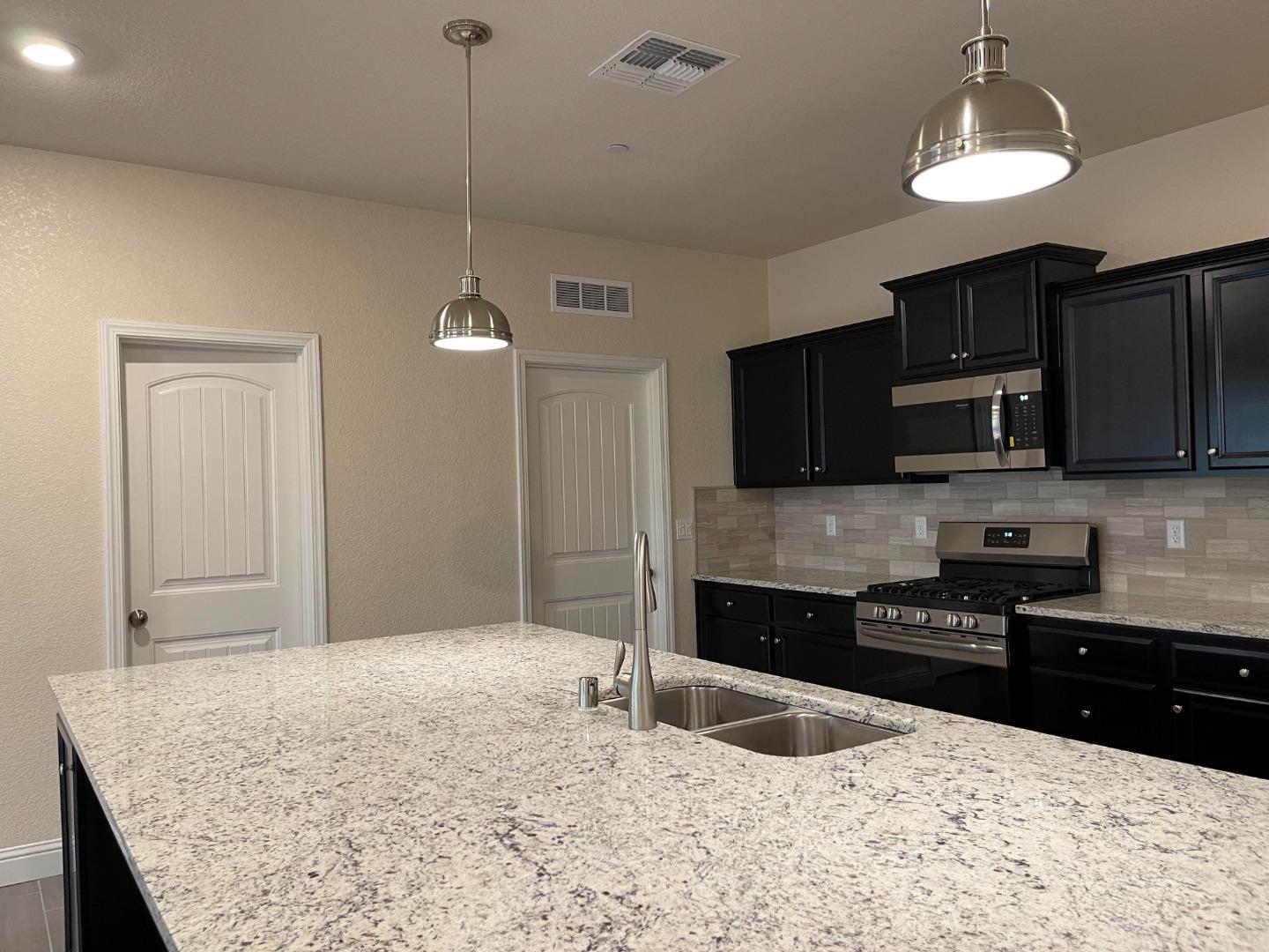 2411 Gabriel Drive Merced, CA 95340 - Photo 5 of 22 a kitchen with stainless steel appliances granite countertop a sink refrigerator and microwave