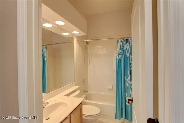 a bathroom with a granite countertop bathtub shower sink vanity and toilet