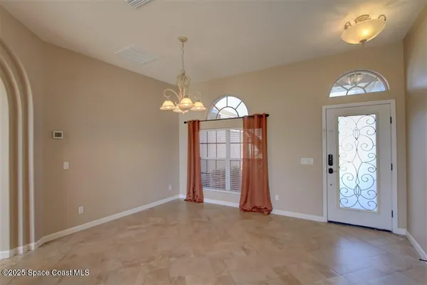 an empty room with chandelier fan and windows