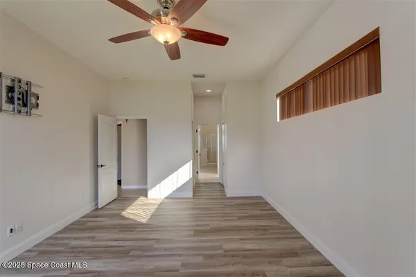 a view of a hallway with wooden floor and a ceiling fan