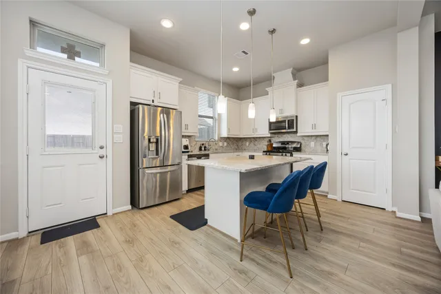 a kitchen with stainless steel appliances a refrigerator a stove a sink dishwasher and a refrigerator with wooden floor