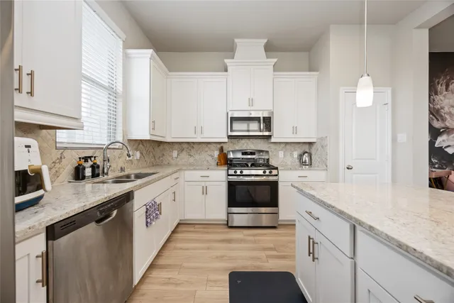 a kitchen with stainless steel appliances kitchen island granite countertop a sink dishwasher stove and white cabinets