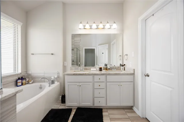 a spacious bathroom with a double vanity sink mirror and a bathtub