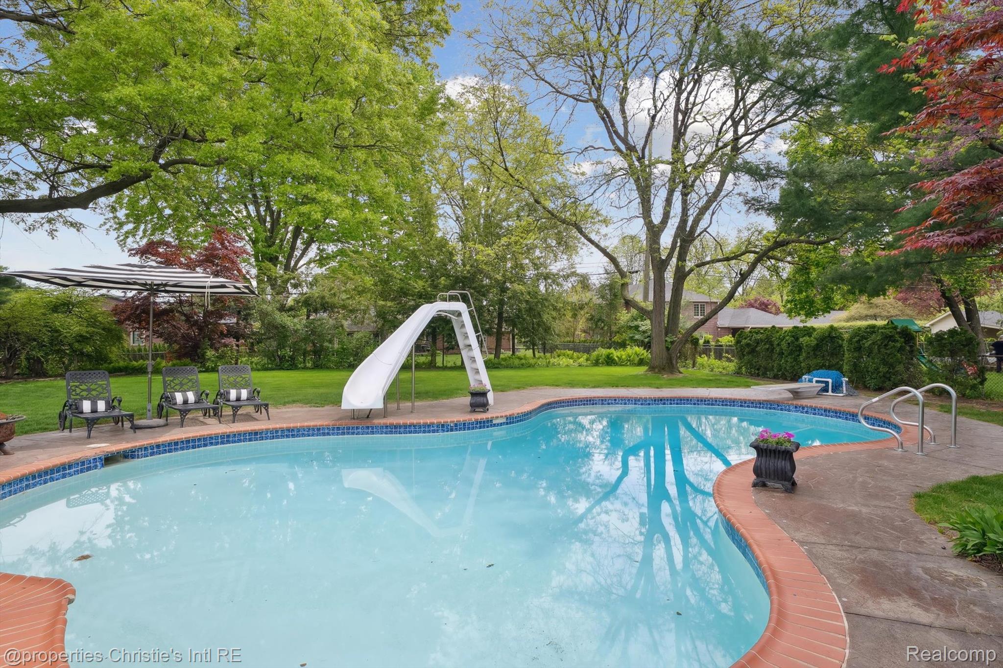 511 South Gulley Road Dearborn, MI 48124 - Photo 42 of 43 Expansive backyard featuring a free-form swimming pool with a slide, brick coping, and a surrounding concrete patio