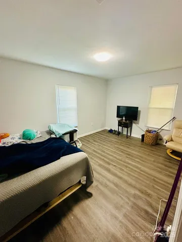 a bedroom with a bed lamp on desk and a window