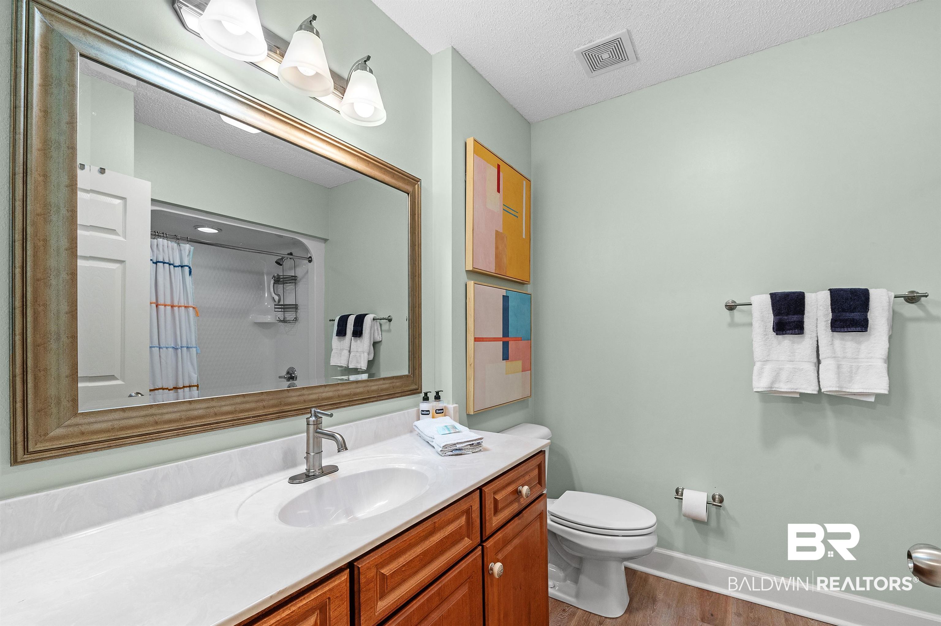 27582 Canal Road, Unit 2104 Orange Beach, AL 36561 - Photo 29 of 35 Bathroom featuring hardwood / wood-style floors, vanity, tub/shower combo, and toilet