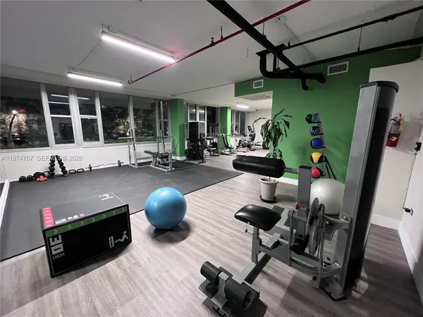 a living room with furniture gym equipment and a large window