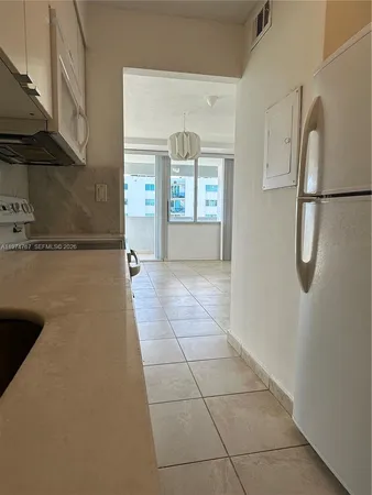 a view of a hallway with a white cabinet and a refrigerator