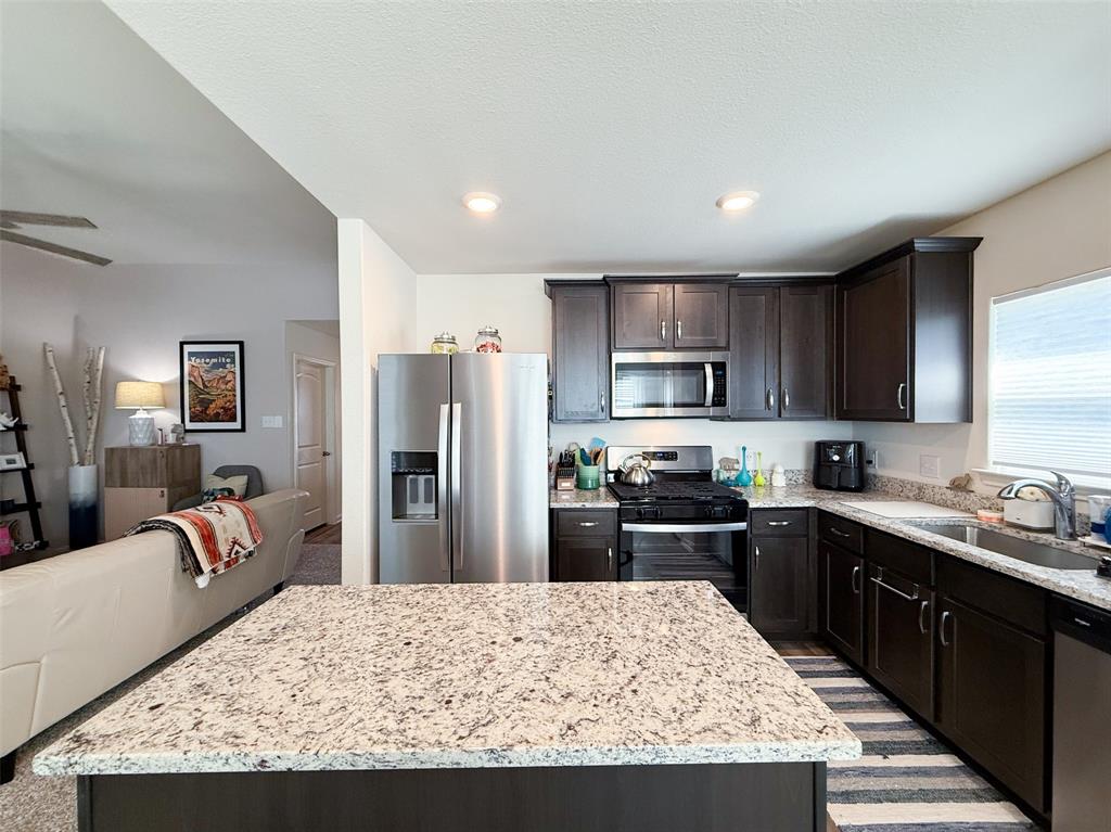 13507 Granite Park Road Ponder, TX 76259 - Photo 9 of 28 a kitchen with stainless steel appliances kitchen island granite countertop a refrigerator stove sink and dishwasher