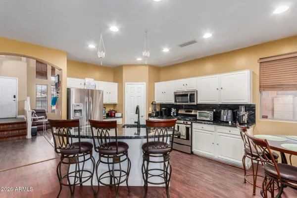 a kitchen with stainless steel appliances a dining table chairs and granite counter tops