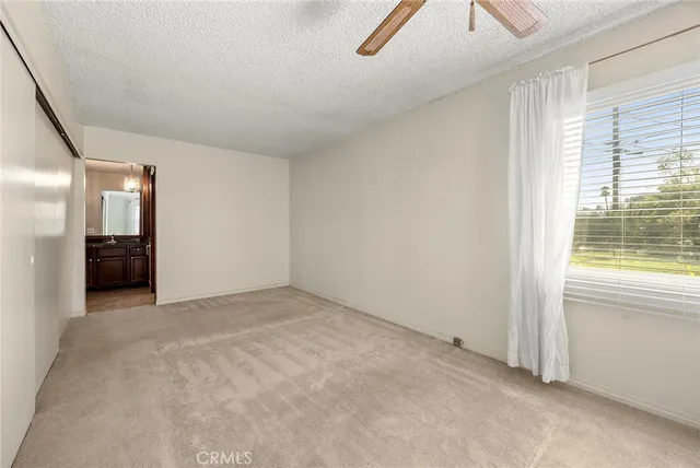 an empty room with windows and fan