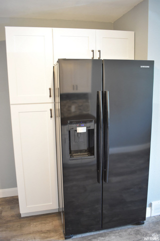 490 Averett Avenue Springville, UT 84663 - Photo 14 of 14 Built-in black side-by-side refrigerator with exterior ice and water dispenser, complemented by white shaker-style cabinetry with dark hardware, wood-finish flooring, and light gray walls