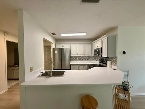 a view of a kitchen with kitchen island a counter top space a sink a refrigerator and windows