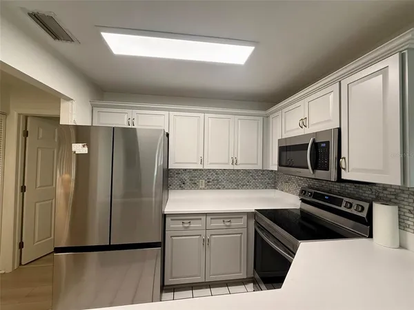 a kitchen with granite countertop a refrigerator stove and microwave