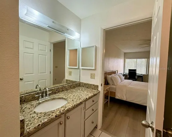 a en suite bathroom with a granite countertop sink and a mirror