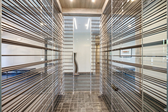 1575 Old Ranch Road Park City, UT 84098 - Photo 12 of 45 Glass panel walls with horizontal metal accents, gray stone tile flooring, and wood-paneled ceiling