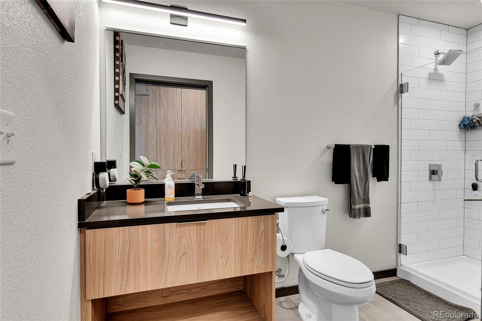 603 Inca Street, Unit 301 Denver, CO 80204 - Photo 8 of 21 a bathroom with a granite countertop sink a toilet a mirror and shower