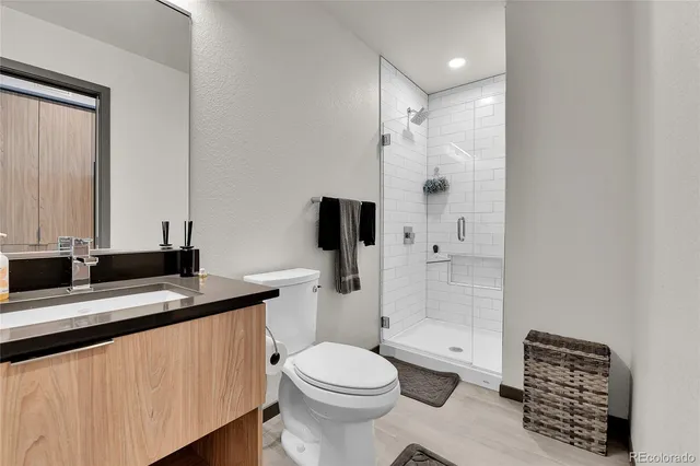 a bathroom with a granite countertop sink toilet mirror and shower