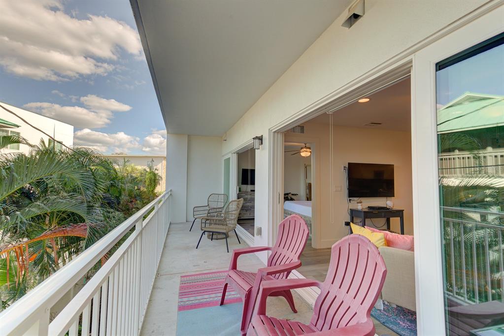 15305 1st Street East, Unit 202 Madeira Beach, FL 33708 - Photo 11 of 40 a balcony with chairs and a flat screen tv